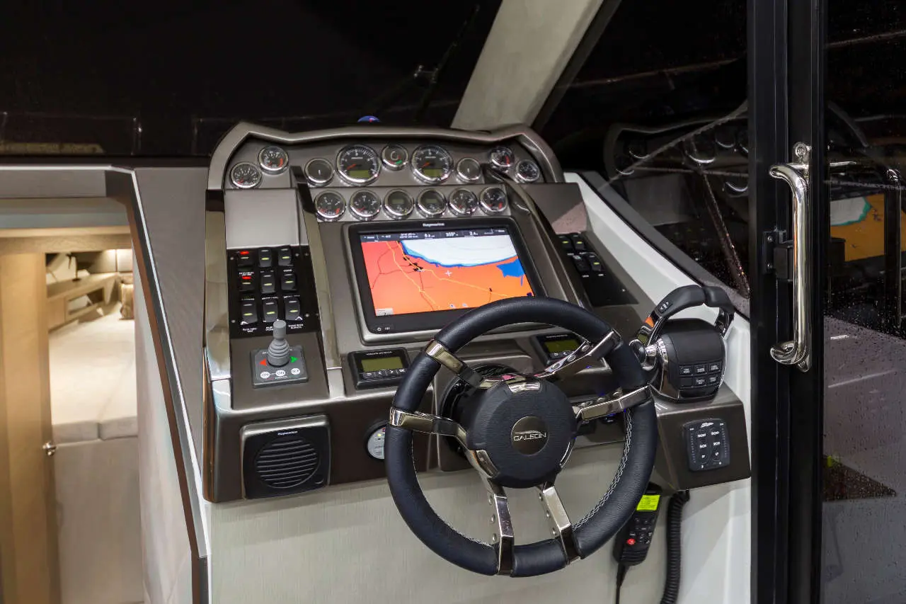 Boat dashboard featuring a steering wheel, navigation screen, control buttons, and various gauges for marine operation.