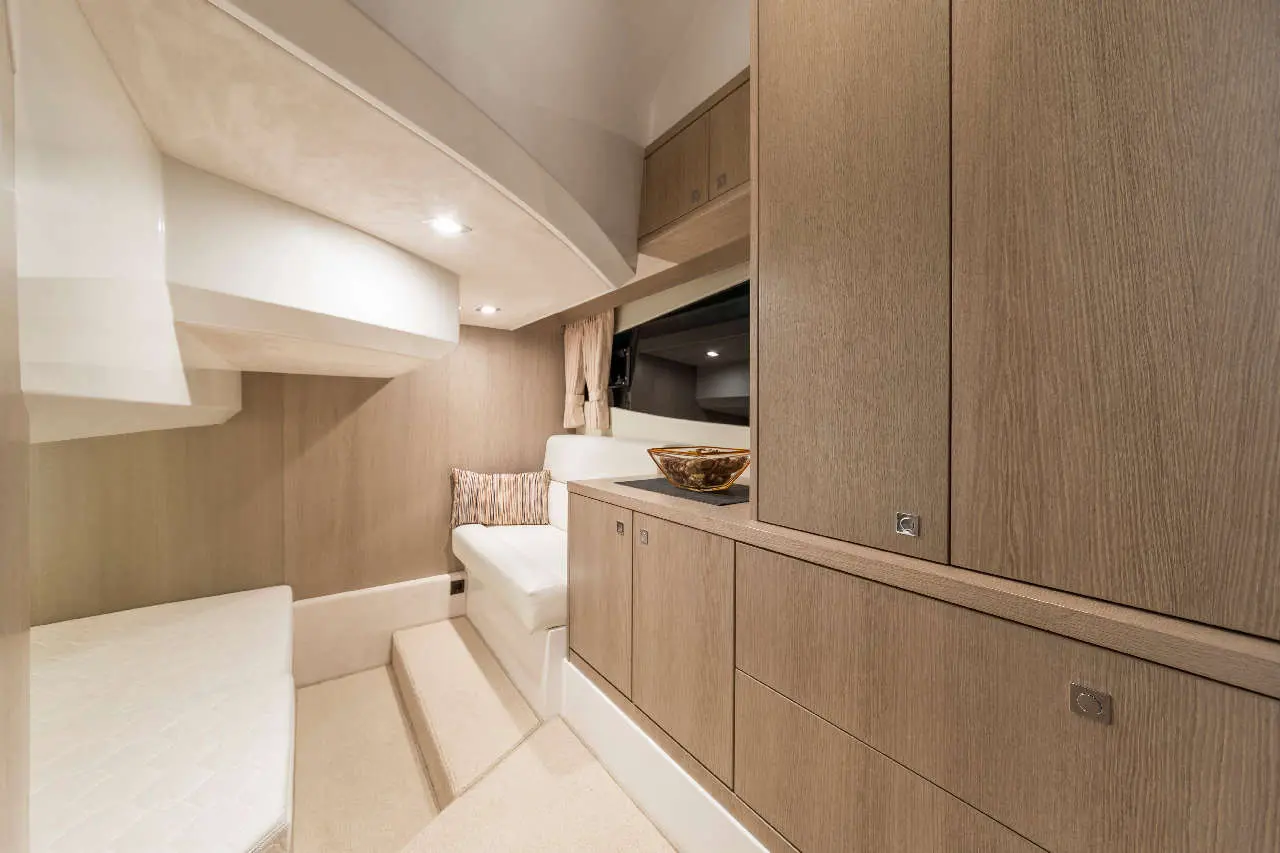 Sleek interior of a modern yacht cabin featuring wooden cabinetry, a white couch, and a decorative bowl on a counter.