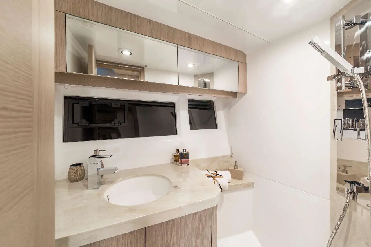 Modern bathroom featuring a circular sink, wooden cabinetry, and a shower with sleek fixtures. Mirror above sink reflects light.