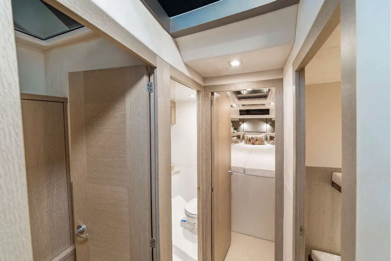 Interior view of a modern yacht showing hallway and three doors leading to a bedroom, bathroom, and storage area.