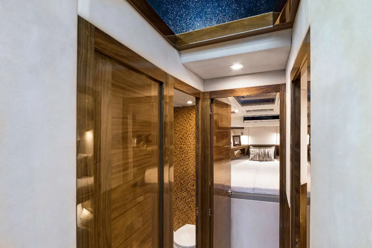 Interior view of a modern hallway leading to a bedroom with wooden doors and a starry sky skylight above.