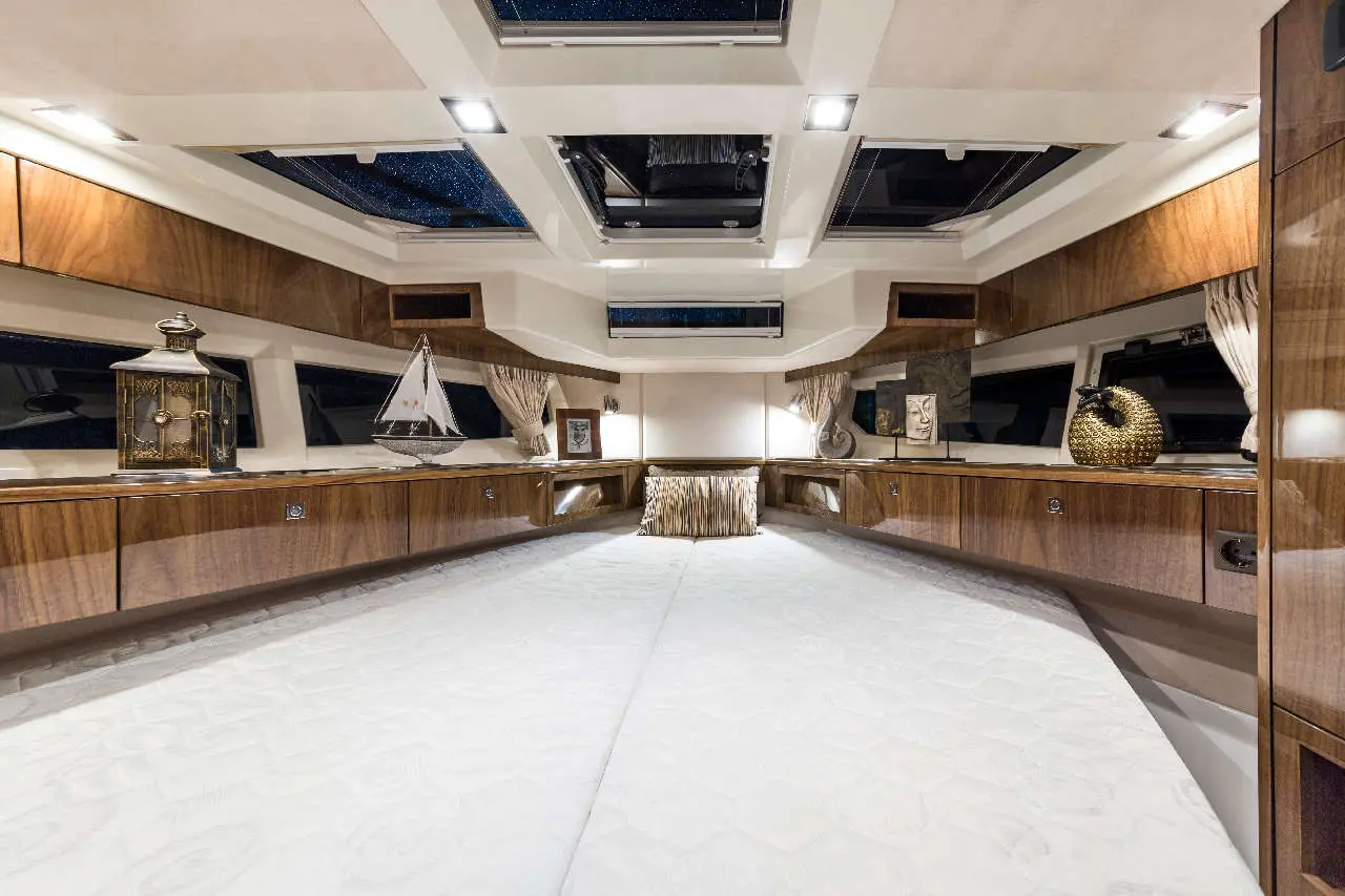 Luxurious yacht interior featuring wooden cabinets, decorative pillows, and skylights under a starry ceiling.