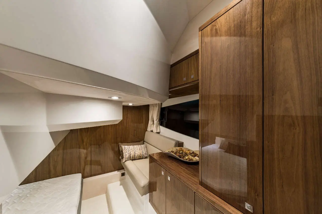Modern yacht interior featuring wooden cabinetry, a seating area with a pillow, and a decorative bowl on the counter.