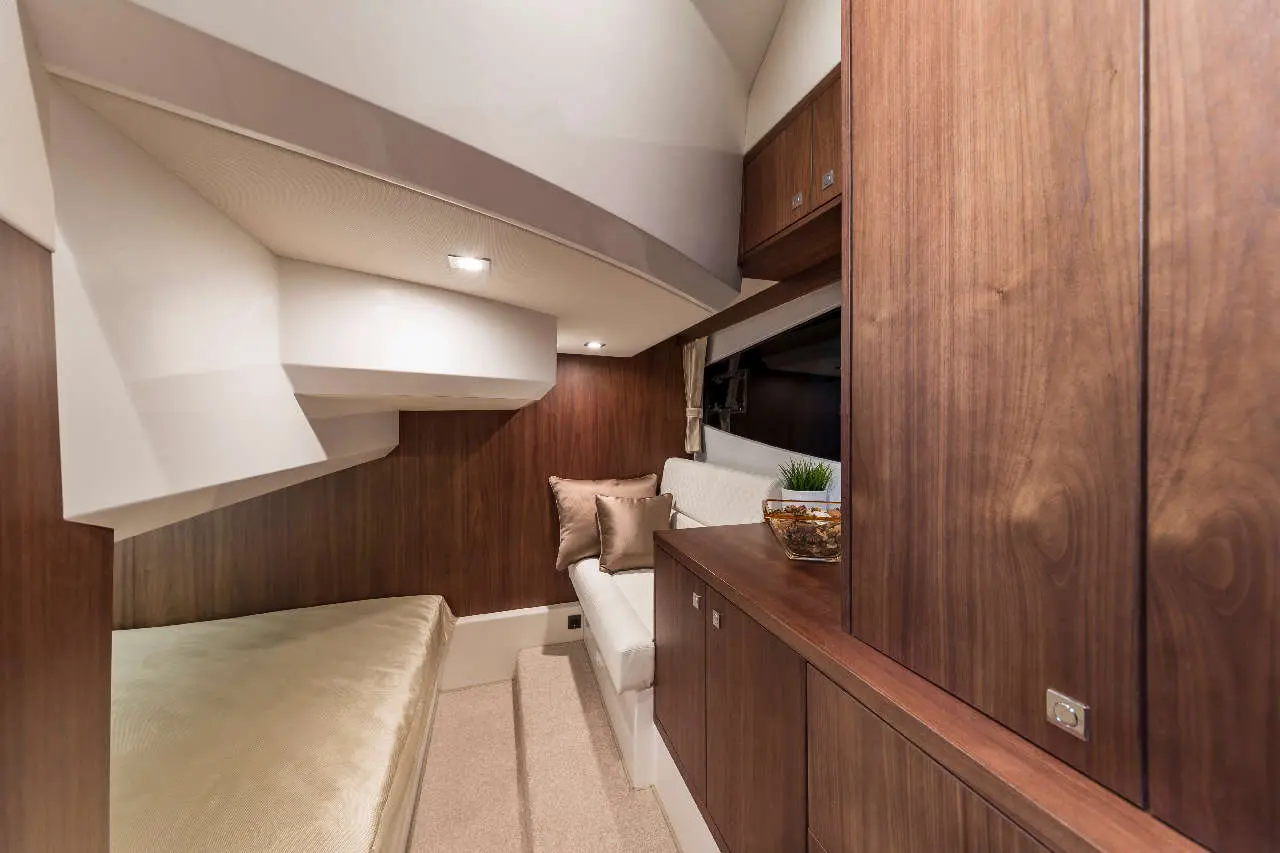Modern boat interior featuring a cosy seating area, wood cabinetry, soft cushions, and ambient lighting.