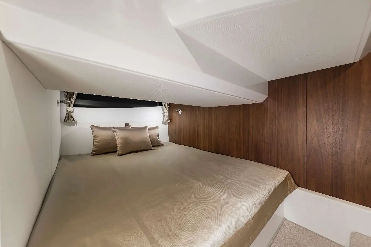 Cozy cabin interior featuring a double bed with gold bedding and matching cushions, wooden wall paneling, and soft lighting.