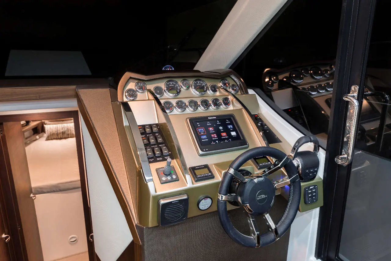Luxury boat dashboard with controls, touchscreen display, and steering wheel, dimly lit for navigation at night.