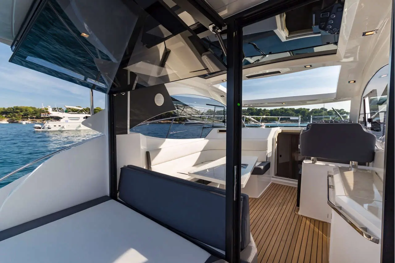 Interior view of a luxury yacht with sleek design, comfortable seating, and a scenic harbour backdrop.