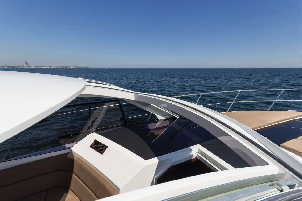 Luxury boat interior with sleek design, clear blue sky, and calm water, showcasing seating and helm area.
