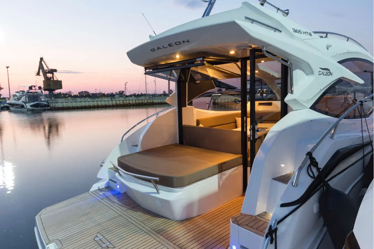 Luxury Galeon 365 HTS yacht with a spacious deck and interior seating, reflecting in calm water at sunset.