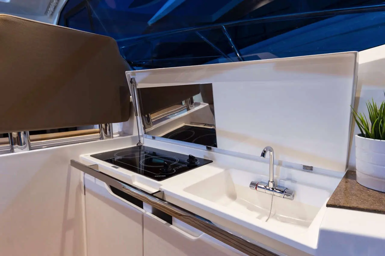 Modern yacht kitchen showcasing an induction hob, sleek sink, and minimalist design with a small plant on the counter.