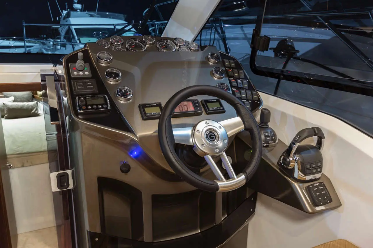 Detailed view of a modern boat's control panel featuring a steering wheel, gauges, and various control buttons.