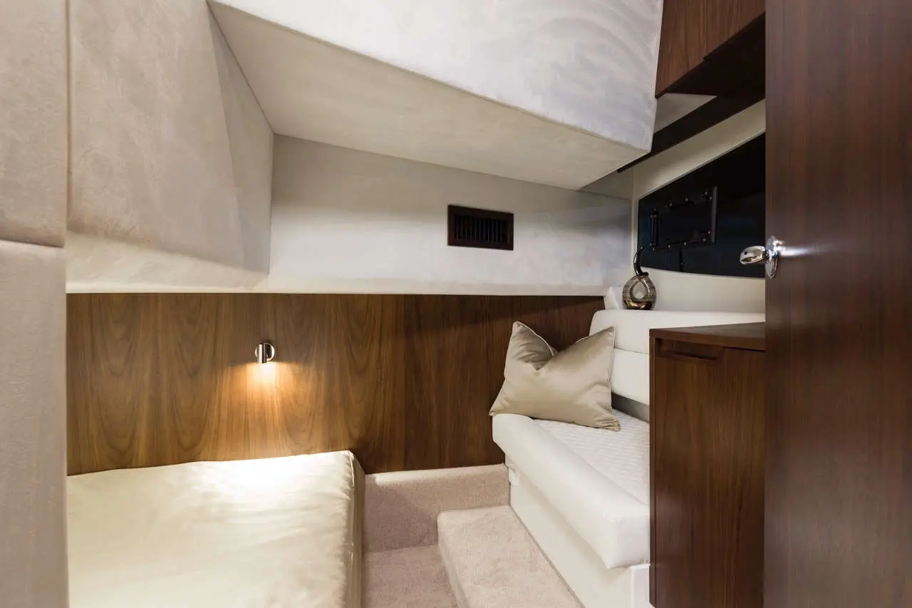 Cozy yacht cabin featuring a bed, plush pillow, subtle lighting, and wooden cabinetry for a relaxing atmosphere.
