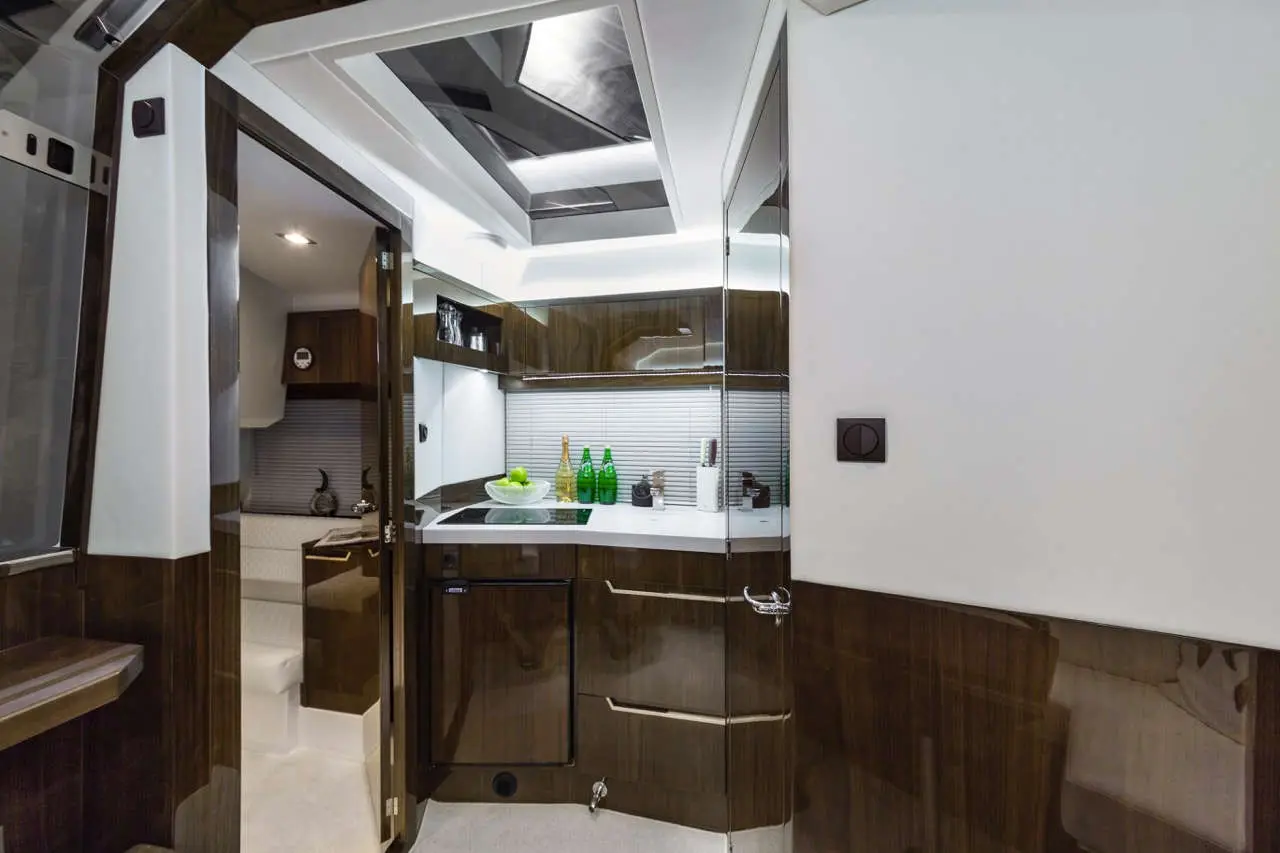 Chic kitchen with sleek cabinetry, a glass vase of green apples, and glass bottles on a modern countertop and grey tiled wall.