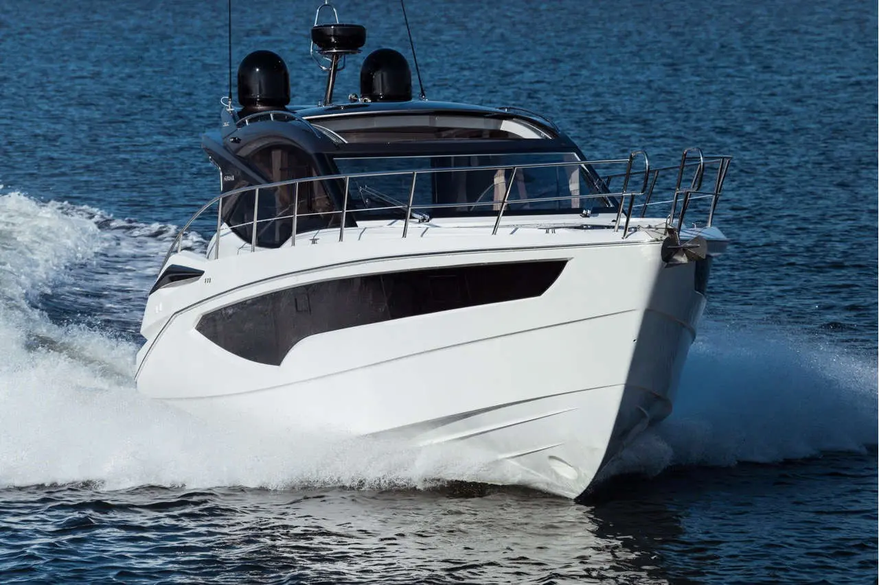White motorboat slicing through water with wake, showcasing sleek design against a blue backdrop.
