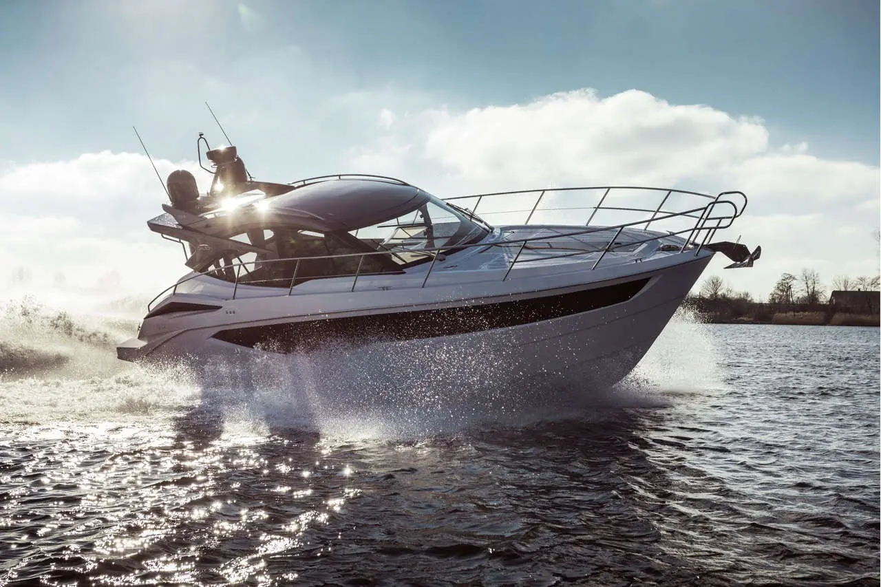 A sleek white motorboat splashes through water under a bright sky, showcasing luxury and adventure on the water.