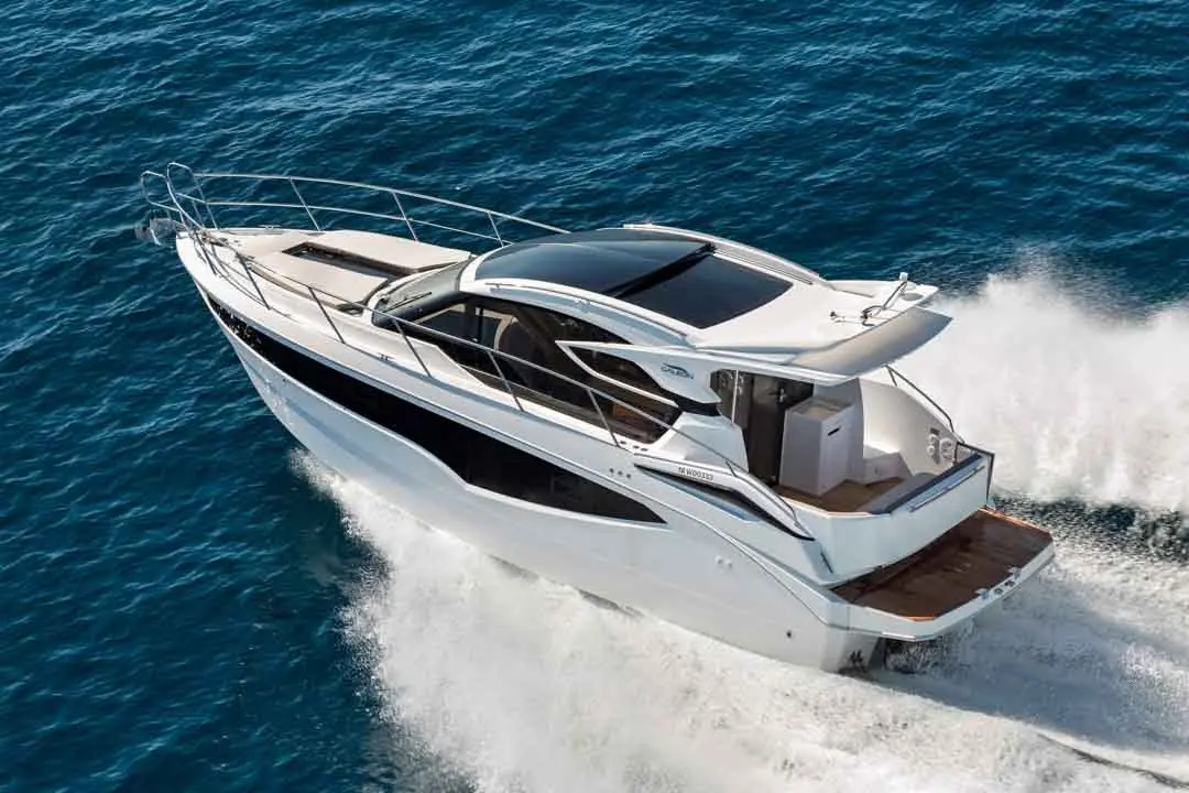 A sleek white yacht cruising over blue ocean waters, creating waves with its speed.