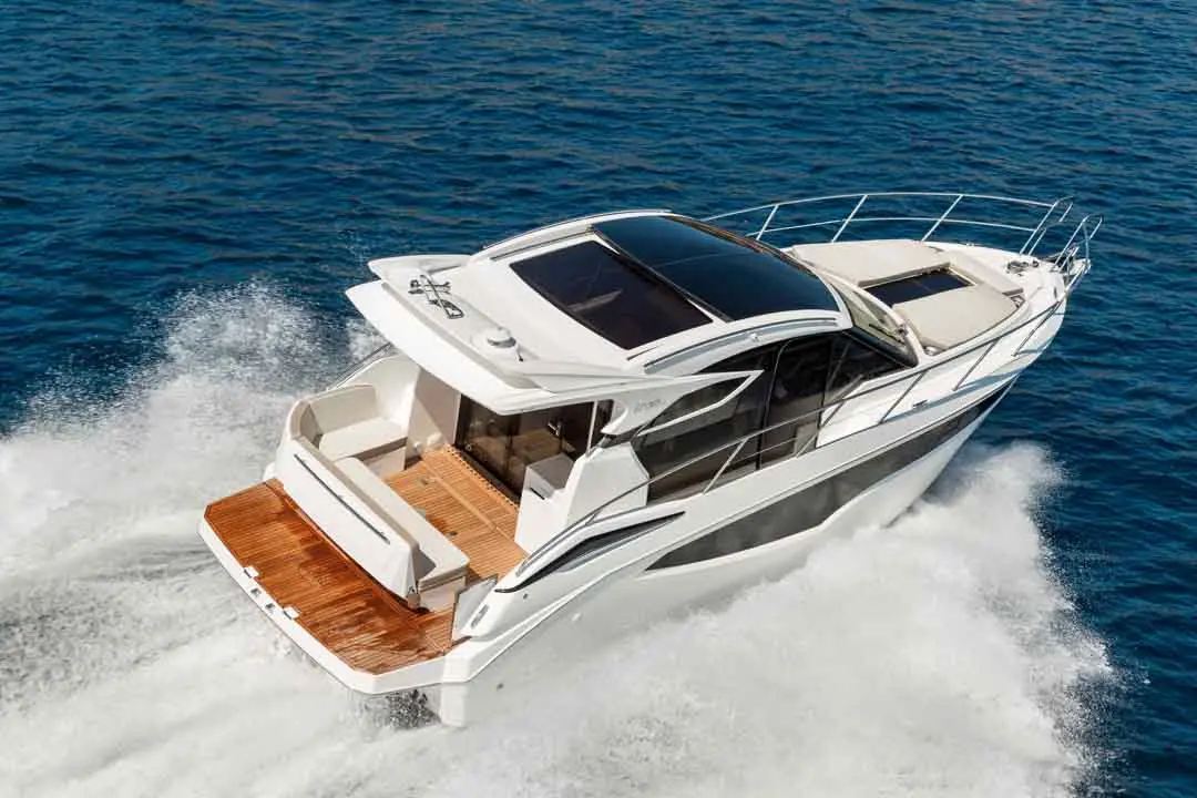 Luxury motorboat cruising over blue water, showcasing its sleek design and wooden deck details.