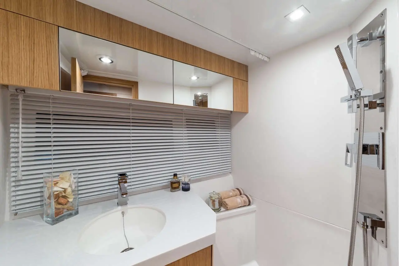 Modern bathroom featuring a round sink, chrome faucet, towels, and a sleek shower with wall-mounted controls.