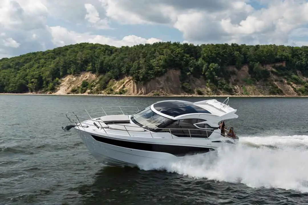 A luxury motorboat speeds across a lake, with lush green hills and a cloudy sky in the background, creating an adventurous scene.