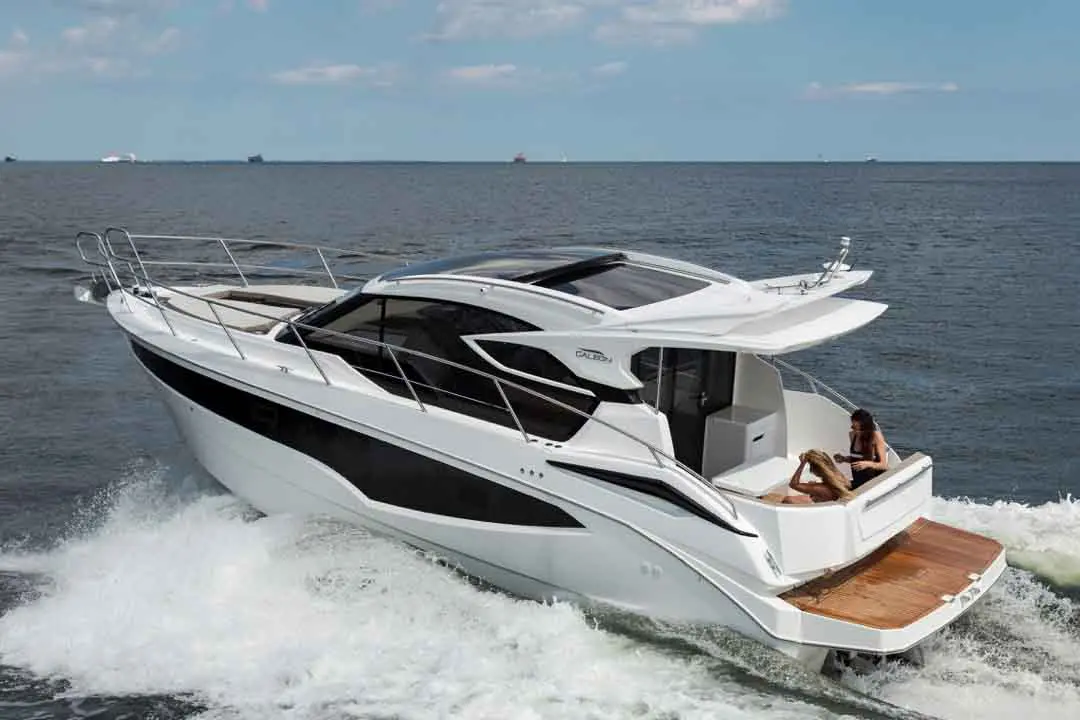 Luxury motor yacht cruising through calm waters with two women relaxing on the deck under the sun.