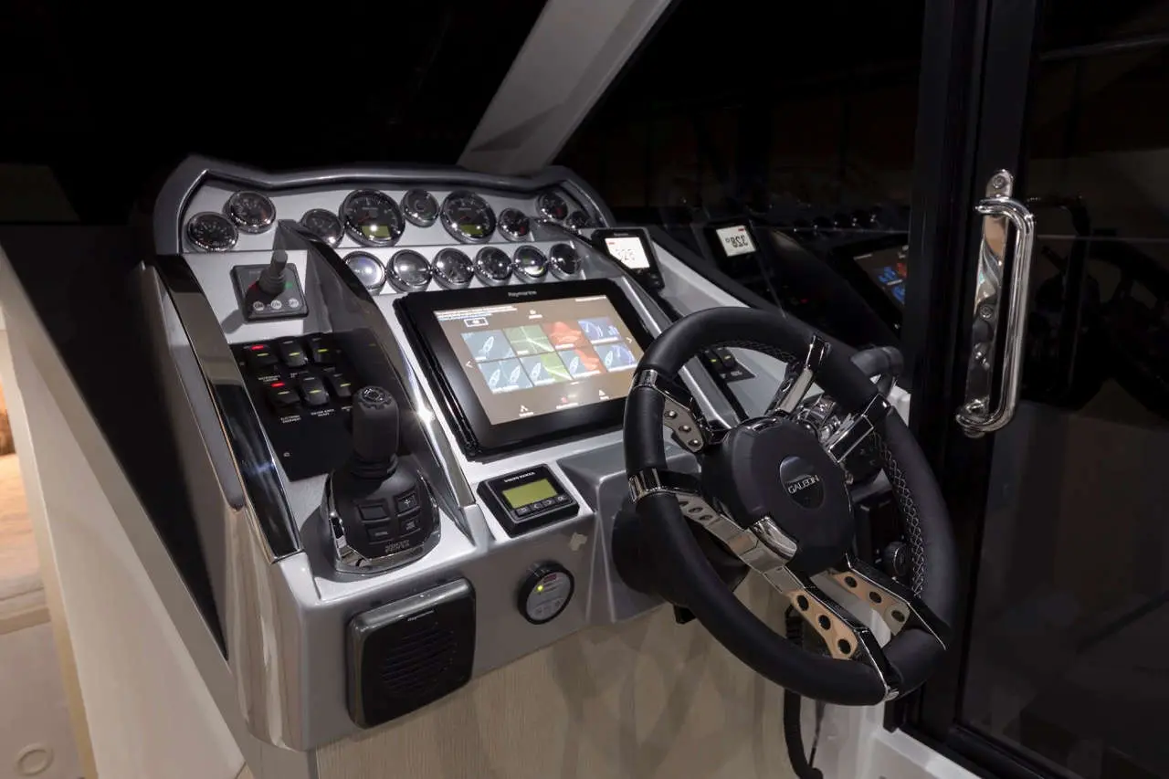 Modern boat cockpit featuring a steering wheel, touchscreen display, controls, and gauges for navigation and operation.