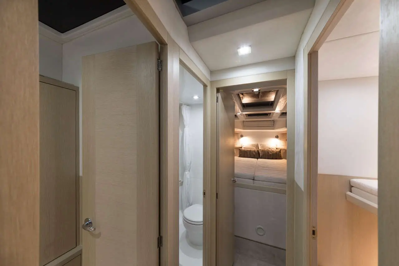 Interior view of a modern cabin showing doors, a bathroom with a toilet, and a cozy bedroom with ambient lighting.