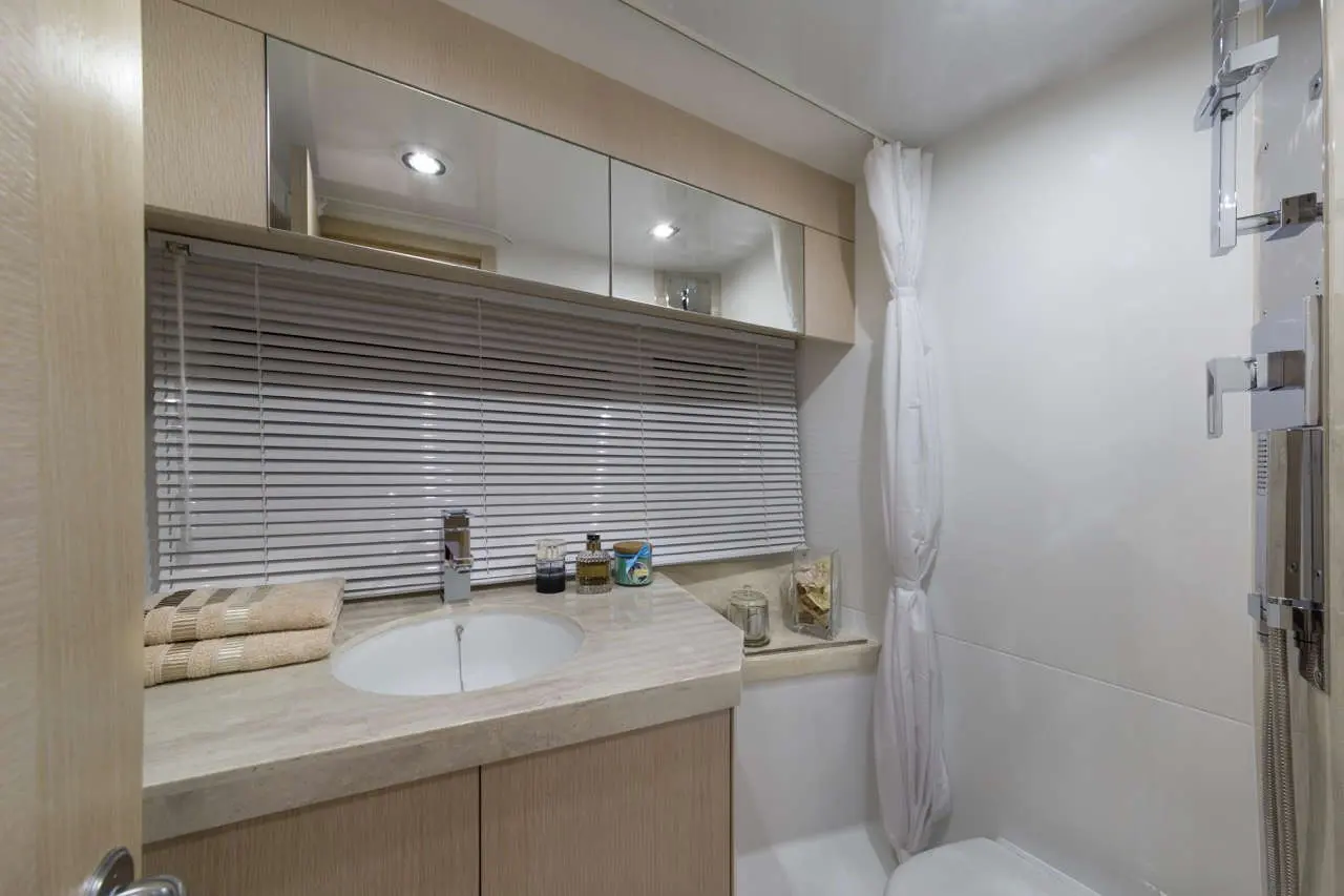 Modern bathroom with a sink, mirror, and shower. Decor includes towels, toiletries, and decorative jars.