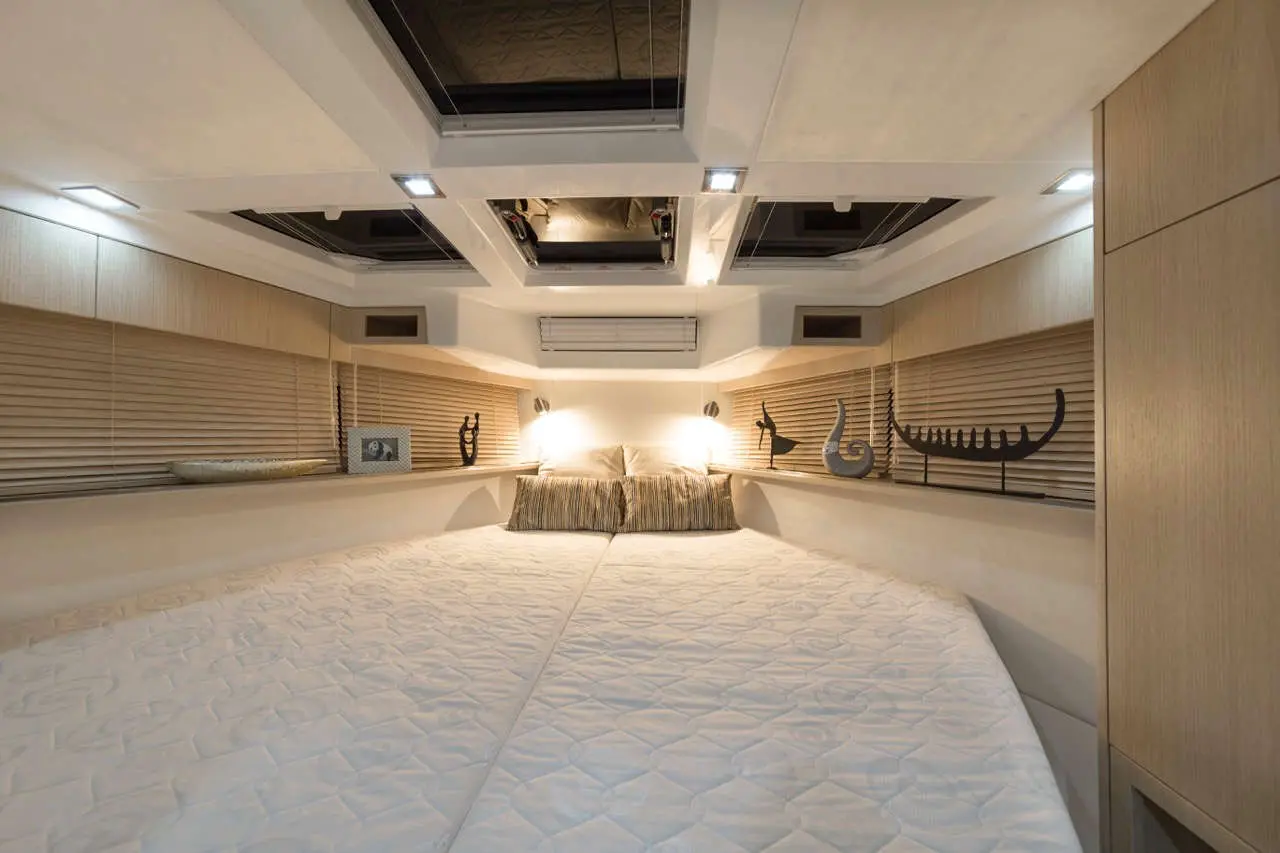 Modern boat interior featuring a spacious double bed, decorative accents, and overhead skylights for natural light.