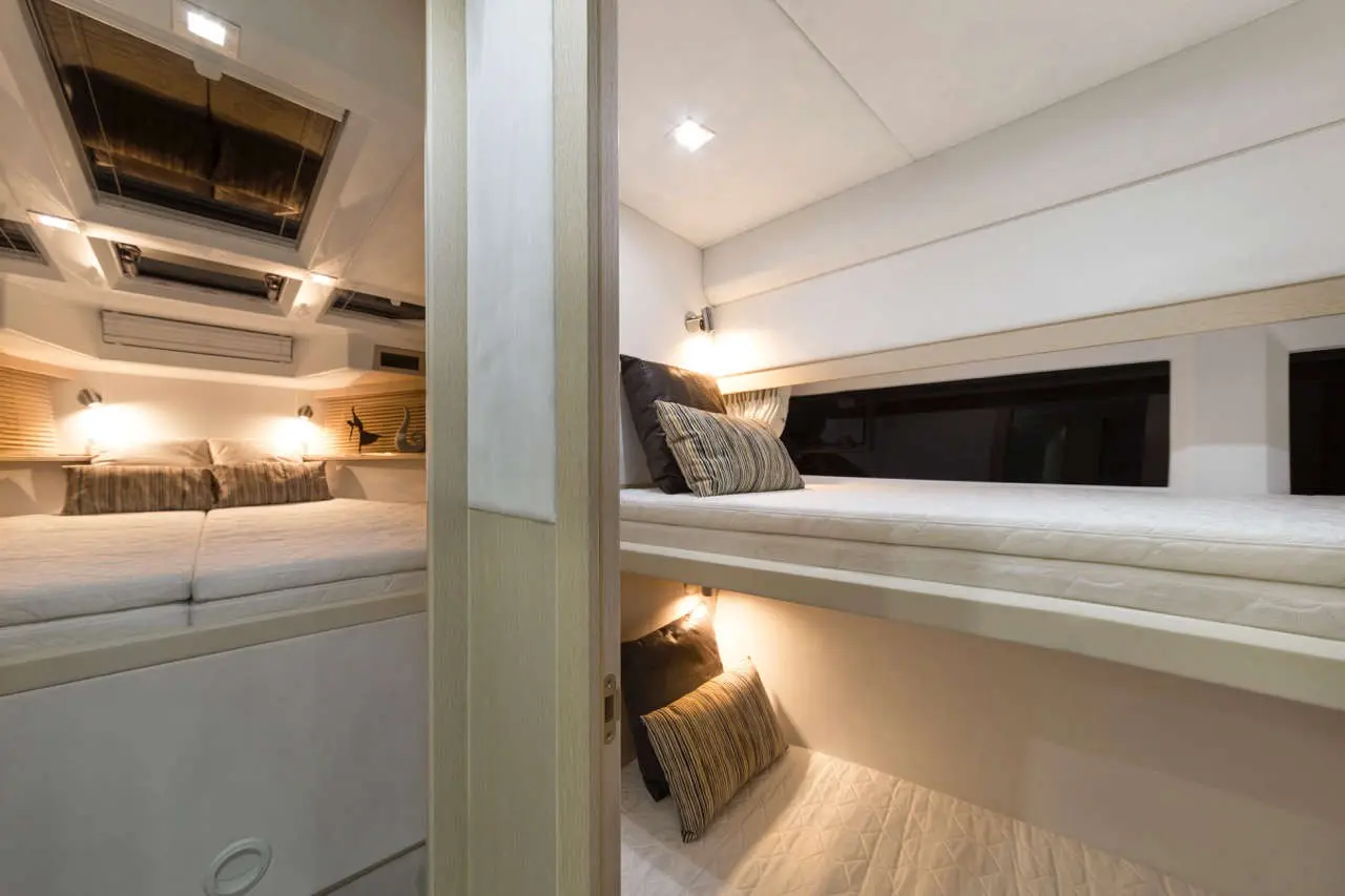 A modern sleeping area with two beds, soft lighting, and decorative pillows, seen through an open door.