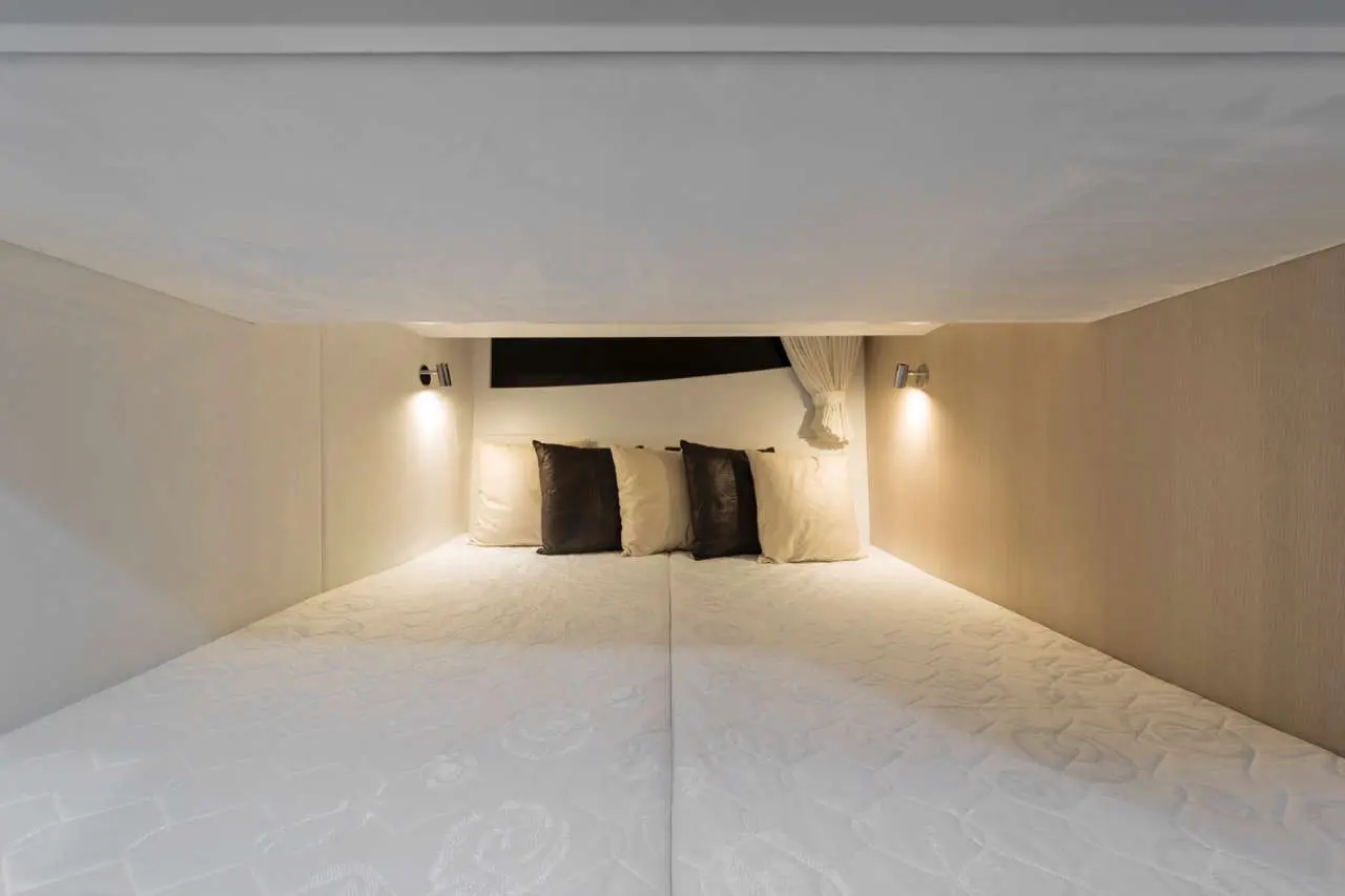 Cozy bedroom with a double bed, two light fixtures, and decorative pillows against a neutral wall backdrop.