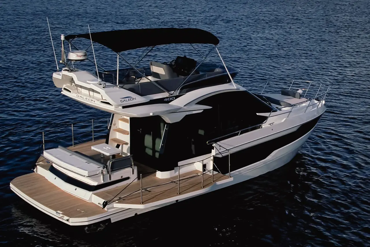 A sleek Galeon 400 motor yacht with a spacious deck and canopy, anchored on calm blue water, showcasing luxury and design.