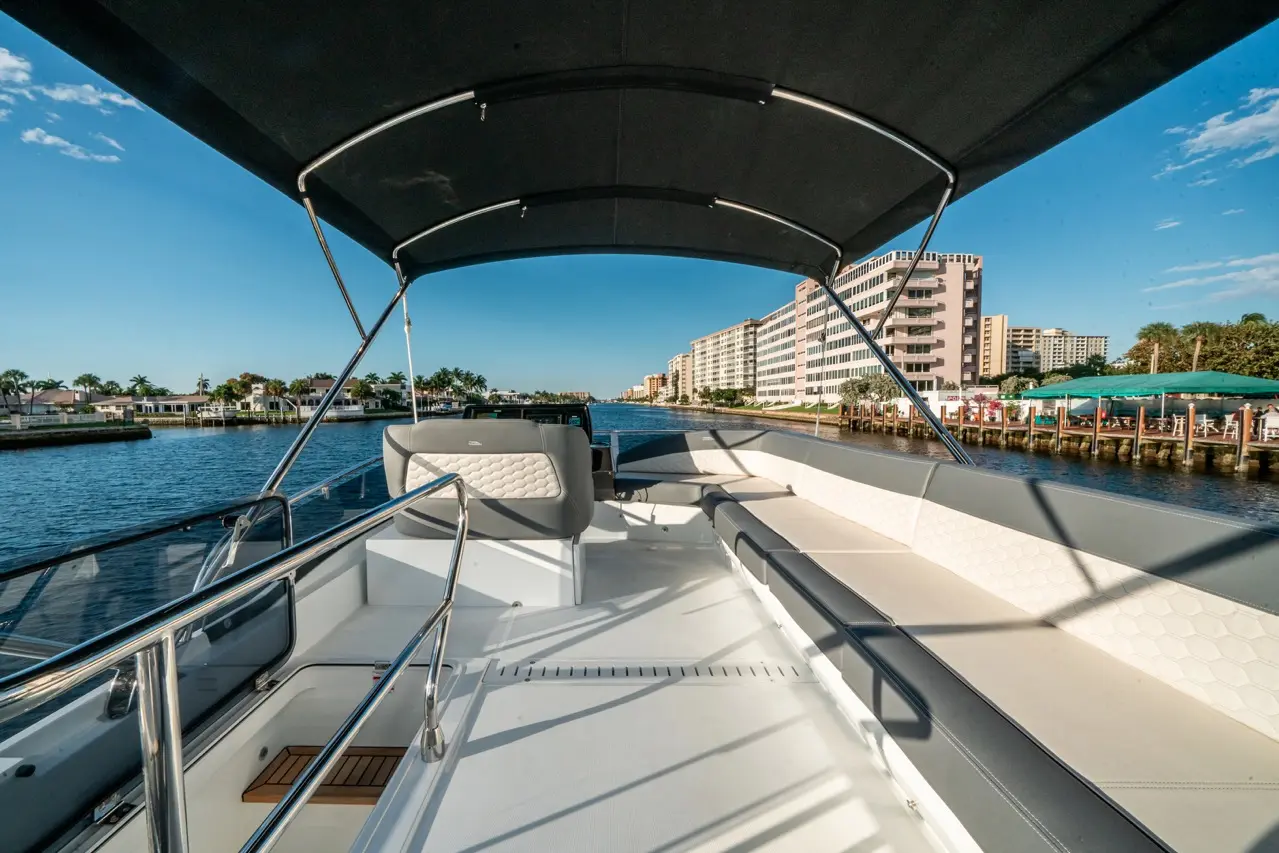 View from the deck of a boat overlooking a canal lined with residential buildings and palm trees under a sunny sky.