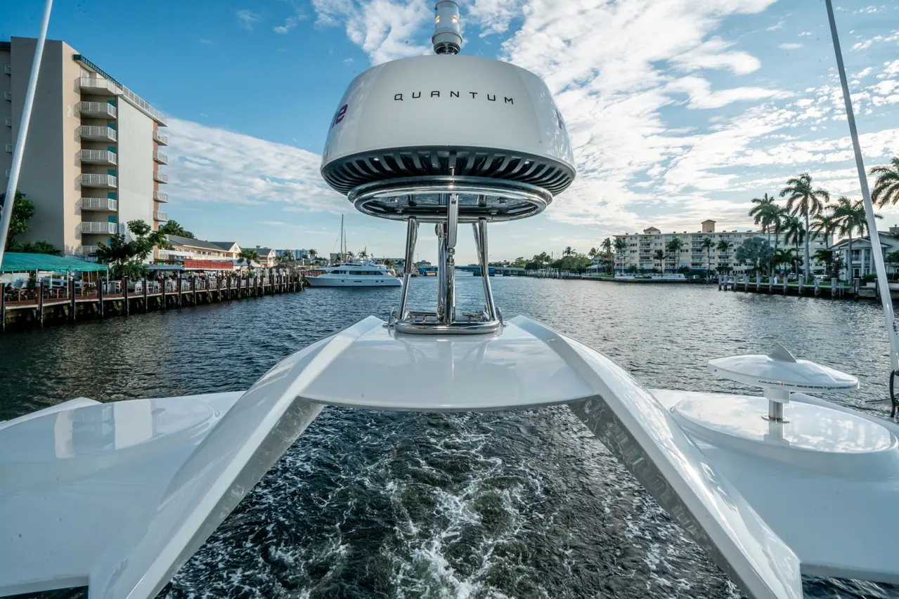 View from the bow of a boat showing a Quantum stabiliser, with a waterfront and buildings in the background under a blue sky.