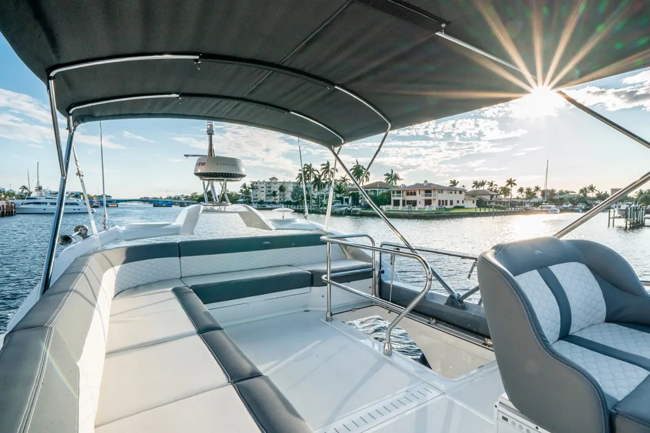 A luxury boat deck overlooking a tranquil waterway with palm trees and waterfront homes, bathed in sunset light.