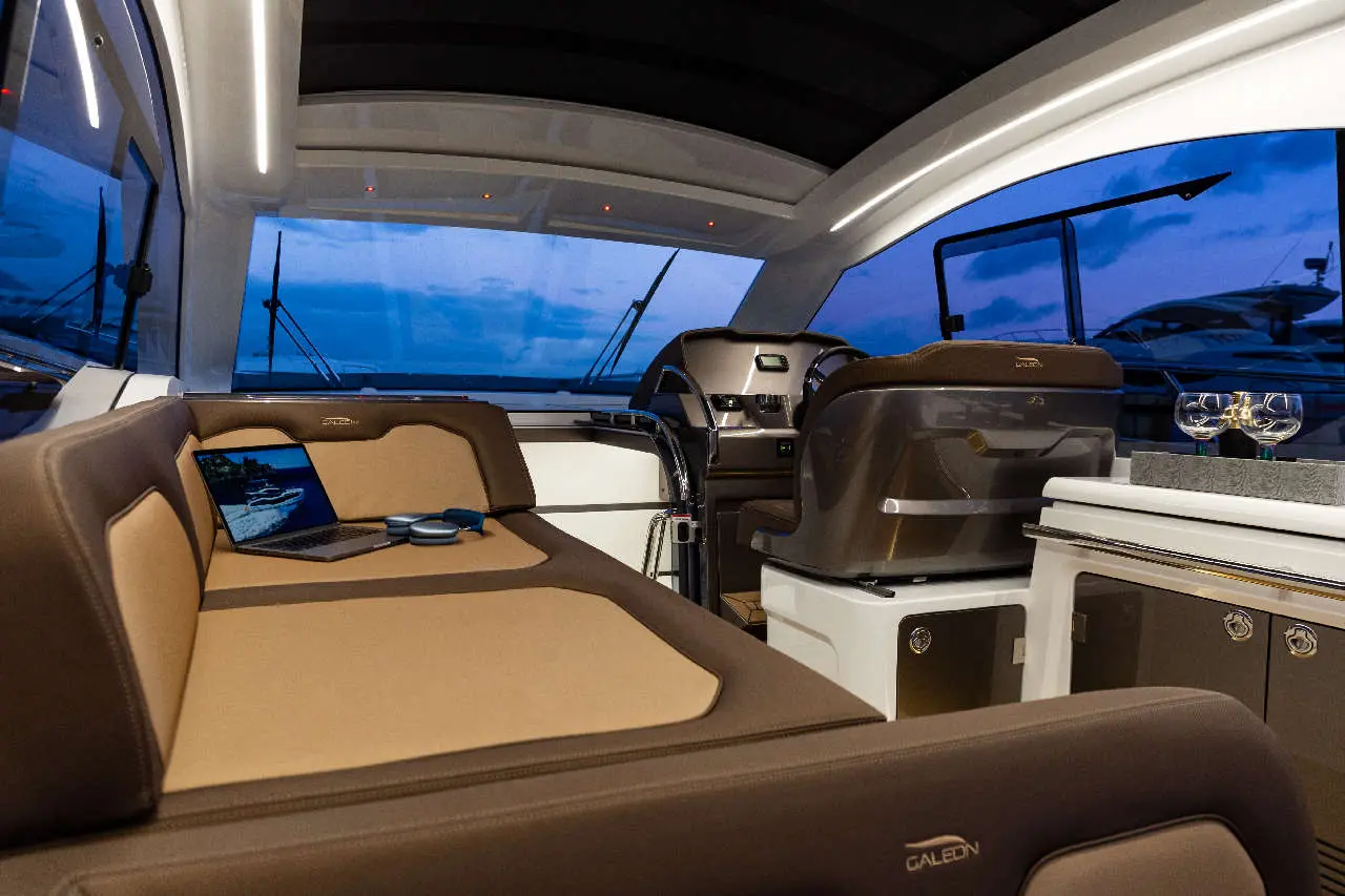 Luxurious yacht interior with a computer, cushions, and elegant decor, showcasing a modern, relaxing atmosphere at dusk.