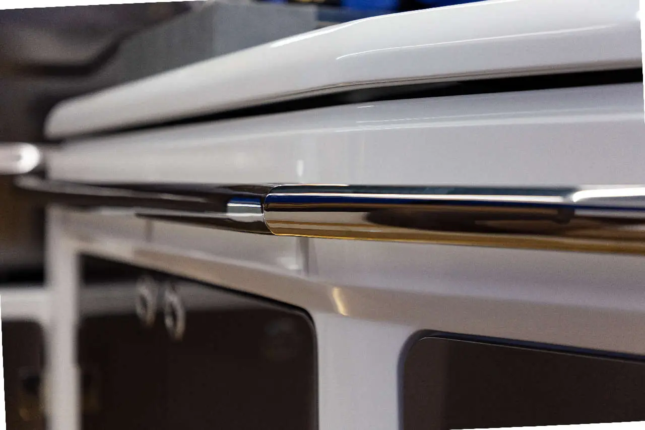 Close-up of a sleek, modern kitchen oven with a shiny stainless steel handle against a white surface.