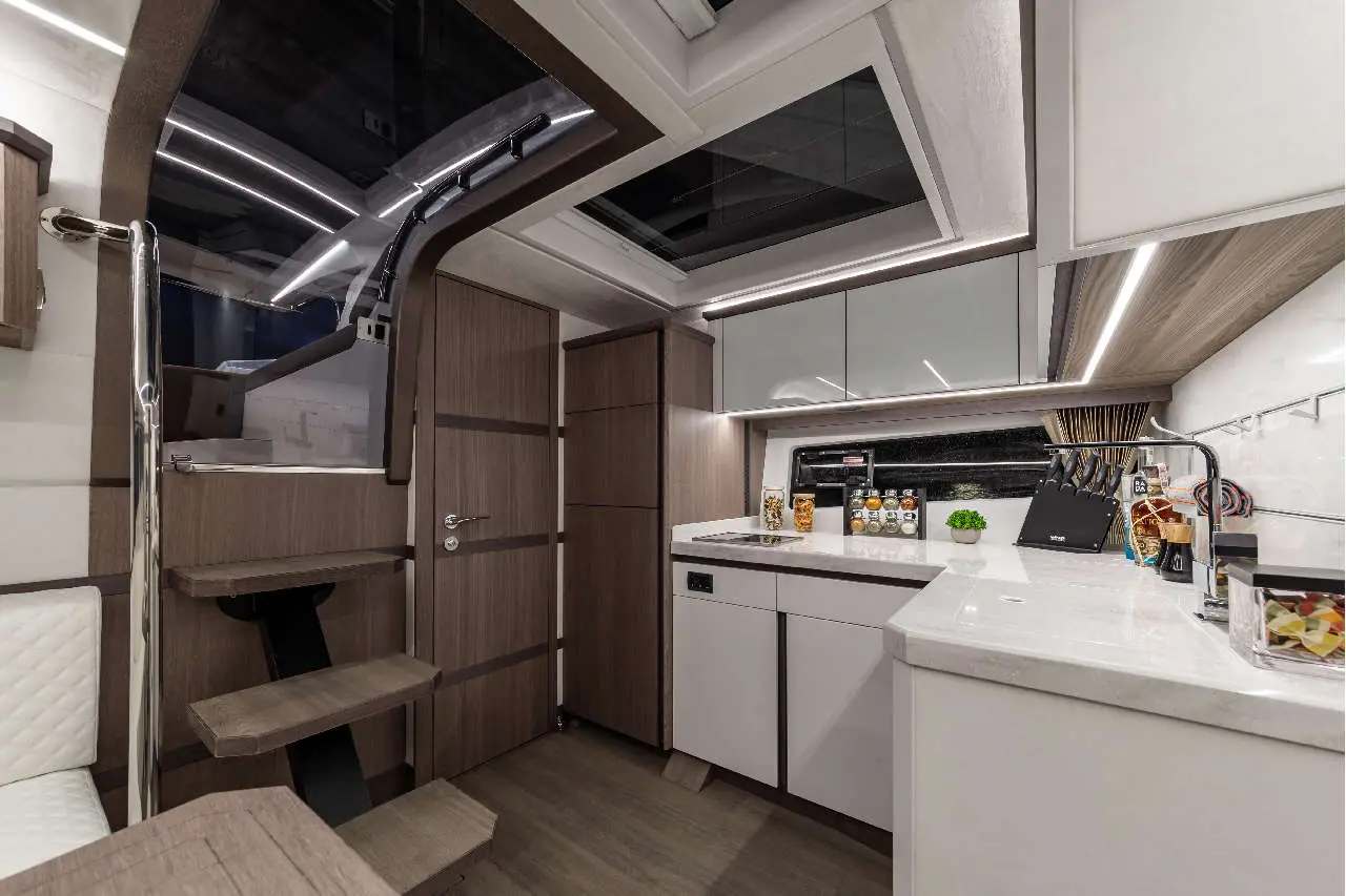 Modern kitchen interior with sleek cabinetry, counter, and decorative plants, featuring windows and stylish lighting.