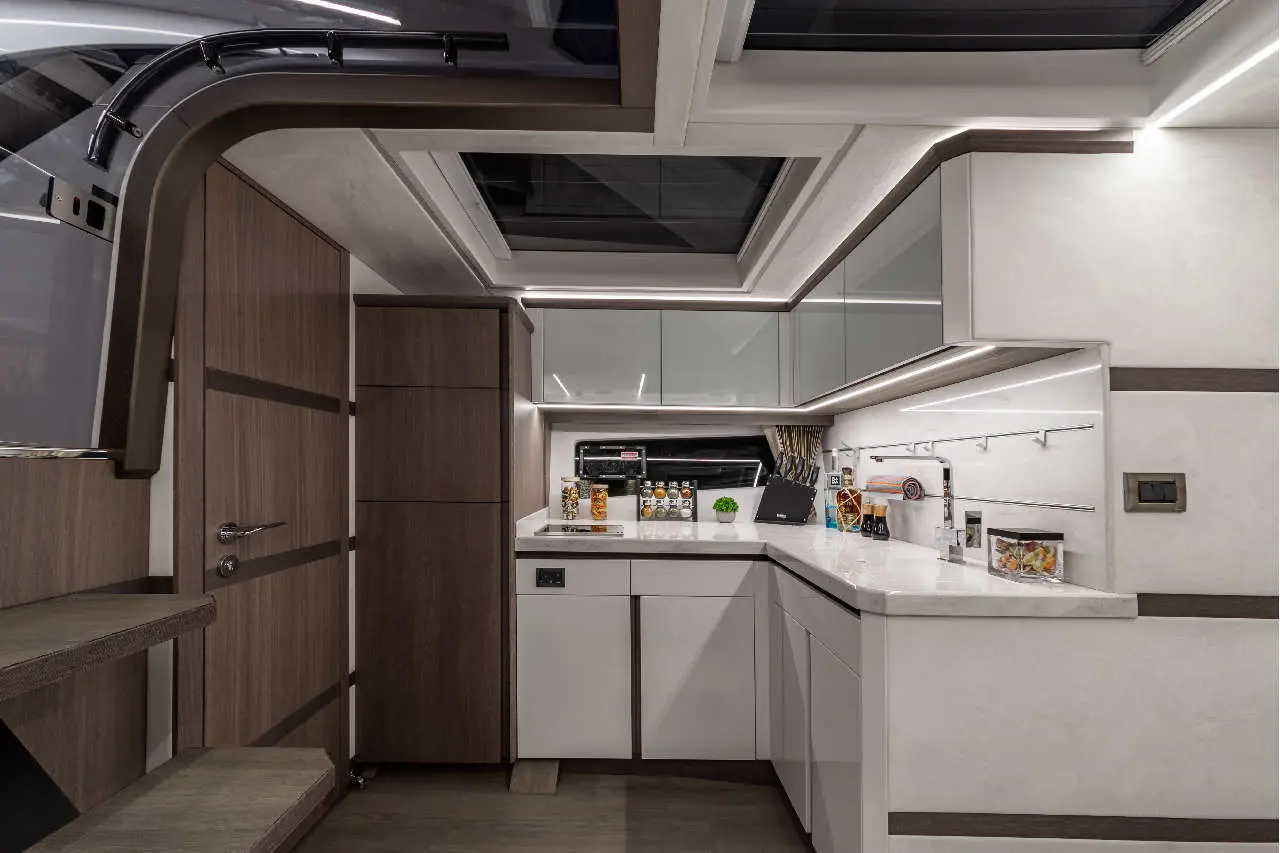 Modern yacht galley showcasing sleek cabinetry, a marble countertop, and organised storage with pantry items displayed.