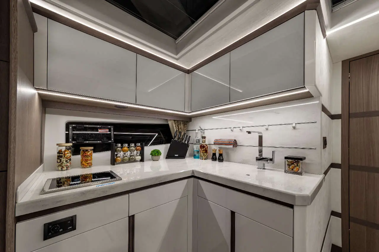 Modern kitchen corner with white cabinets, glass jars, knife block, and a sleek countertop featuring a stove and faucet.