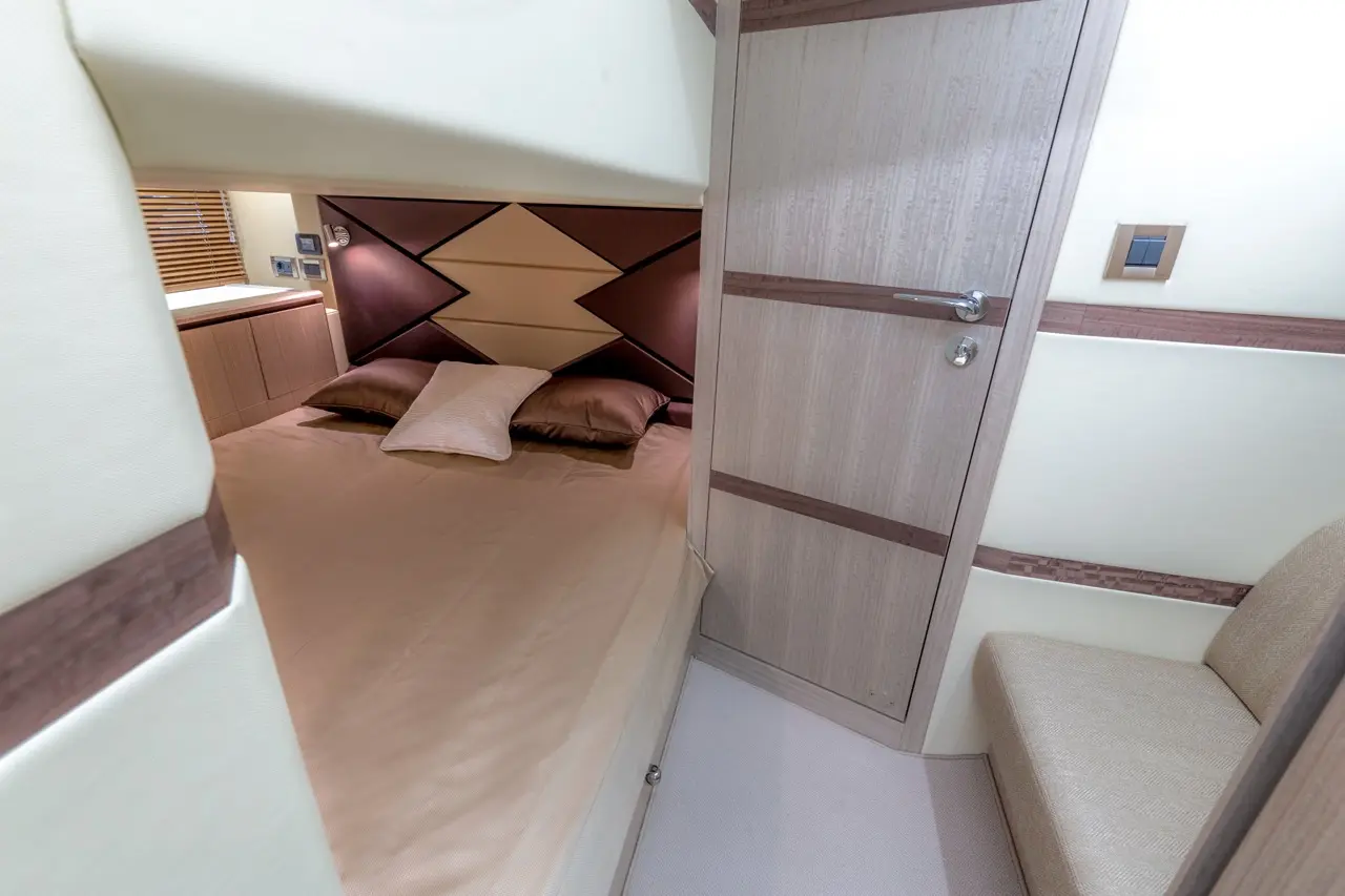 Cozy cabin interior featuring a bed with brown pillows, wooden accents, and a door leading to another space.