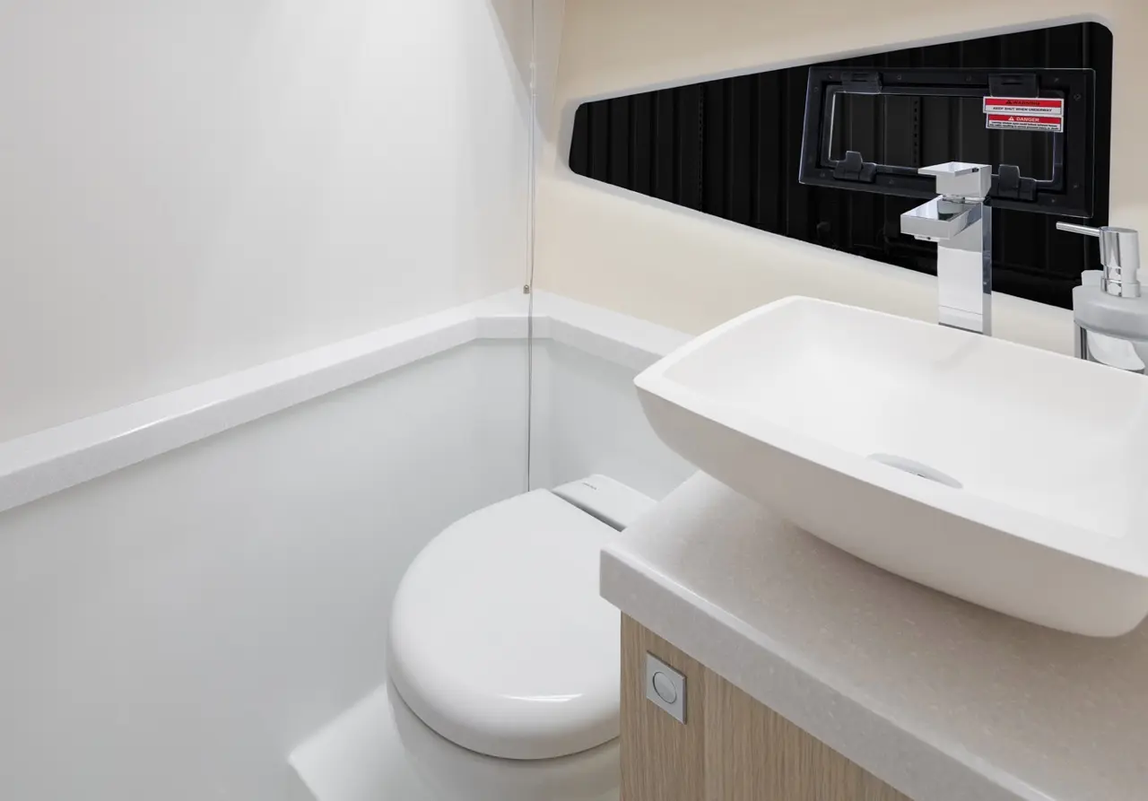 Modern bathroom interior featuring a white toilet, a sleek sink, and a contemporary faucet against a light wall.