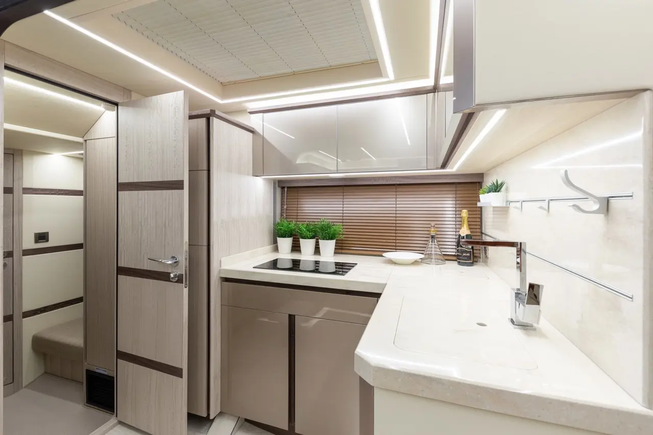 Modern kitchen interior with cream tones, sleek cabinets, potted plants, and wine on the counter, with stylish lighting.