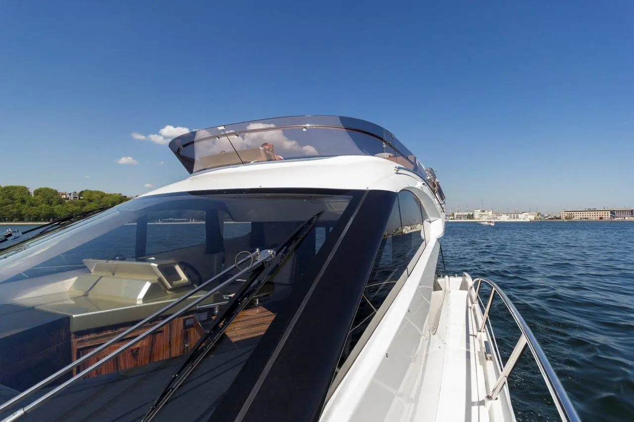 A luxury yacht's cockpit with a clear view of water and shoreline under a blue sky, showcasing boating and leisure activities.