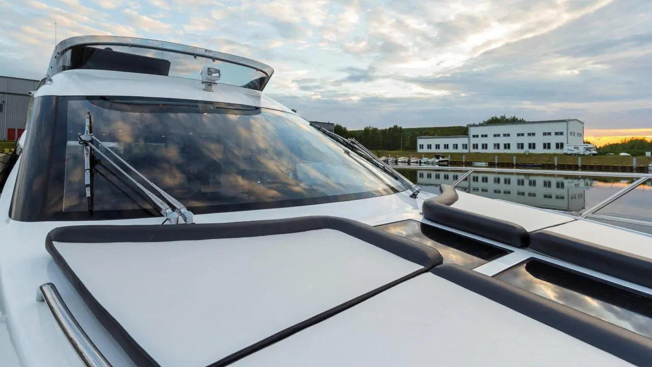 Luxury yacht cockpit view with reflections on water, modern design, and scenic cloudy sky in the background.