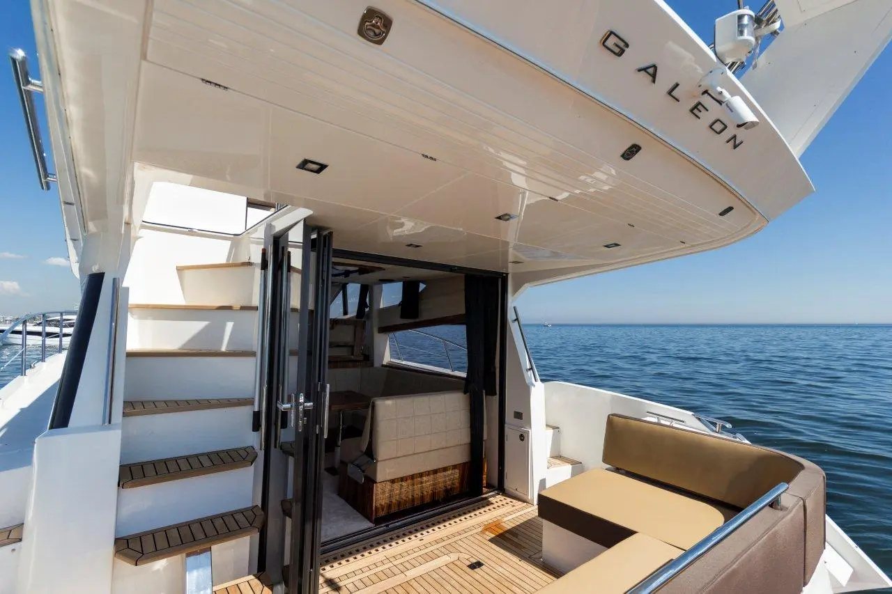 Interior of a luxury Galeon yacht, showing an entryway, stairs, and plush seating, with ocean views in the background.