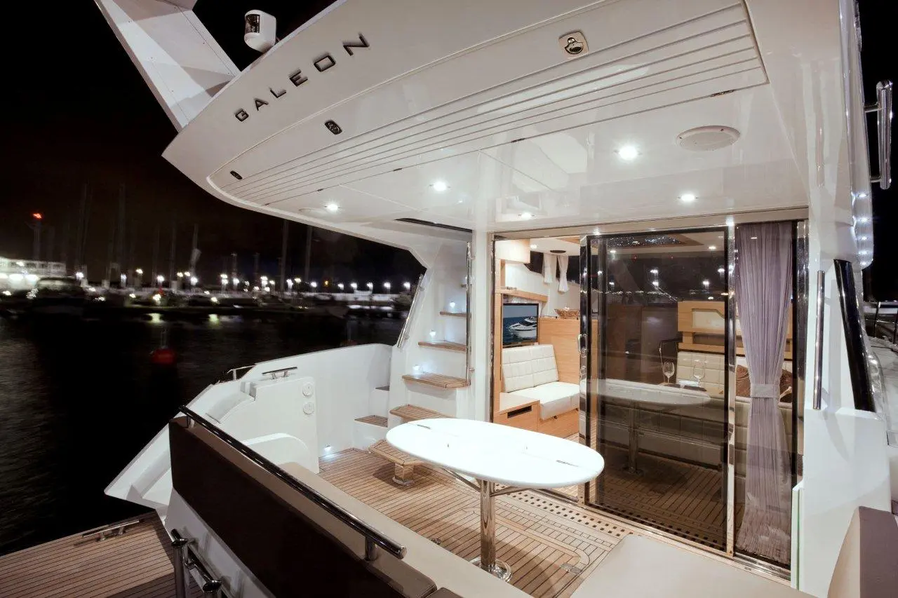 Modern yacht interior with sleek design, featuring a dining table, seating area, and illuminated surroundings in a marina.