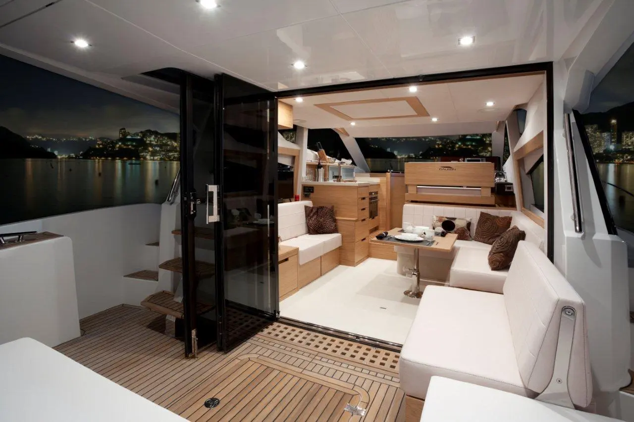 Stylish yacht interior featuring elegant seating, a kitchen area, and a view of a city skyline at night.