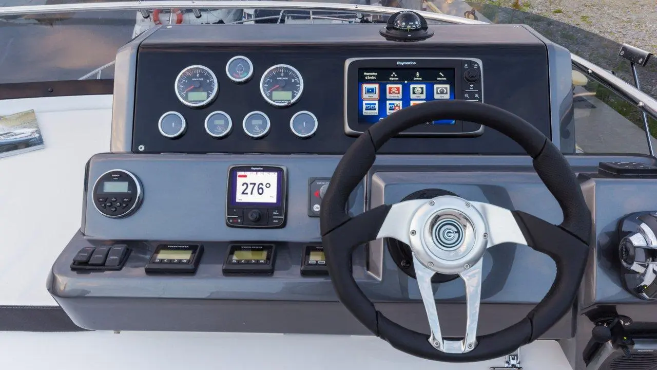 Boat dashboard with instruments, navigation display showing 276°, gauges, and control switches. Sleek modern design.