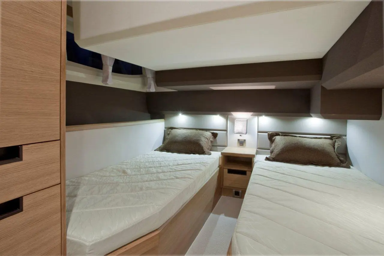 Cozy interior of a cabin featuring two single beds with white mattresses and decorative pillows beside a wooden nightstand.