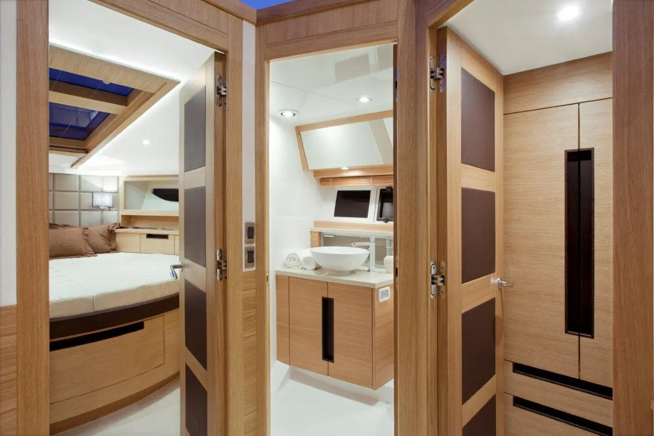 Modern yacht interior featuring wooden doors, a cozy bedroom with a bed, and a stylish bathroom area with a bowl sink.